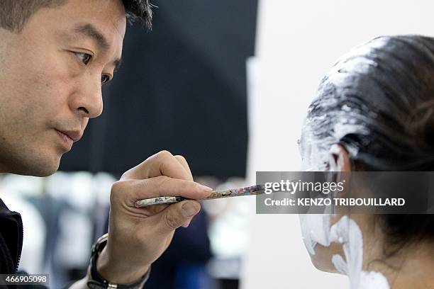 Chinese artist Liu Bolin takes part in a performance on March 19, 2015 in Paris. AFP PHOTO / KENZO TRIBOUILLARD RESTRICTED TO EDITORIAL USE,...