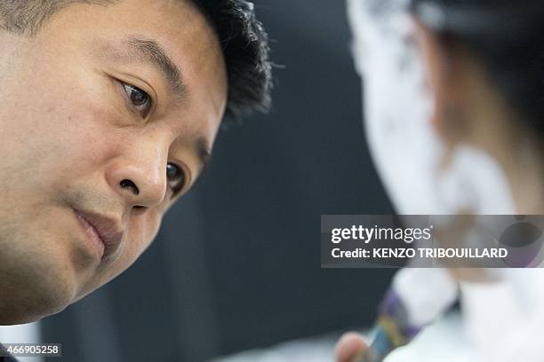 Chinese artist Liu Bolin takes part in a performance on March 19, 2015 in Paris. AFP PHOTO / KENZO TRIBOUILLARD RESTRICTED TO EDITORIAL USE,...