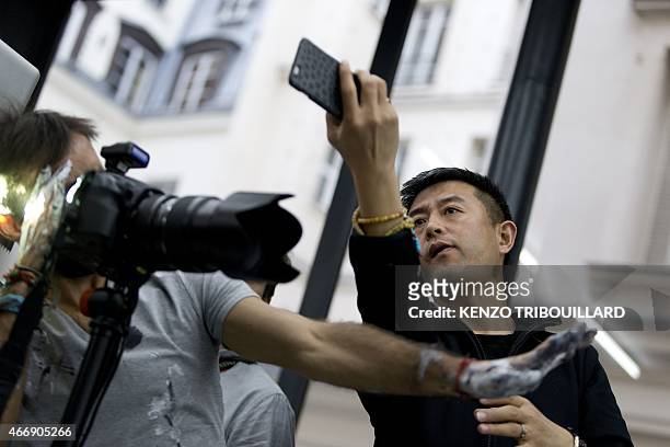Chinese artist Liu Bolin takes part in a performance on March 19, 2015 in Paris. AFP PHOTO / KENZO TRIBOUILLARD RESTRICTED TO EDITORIAL USE,...