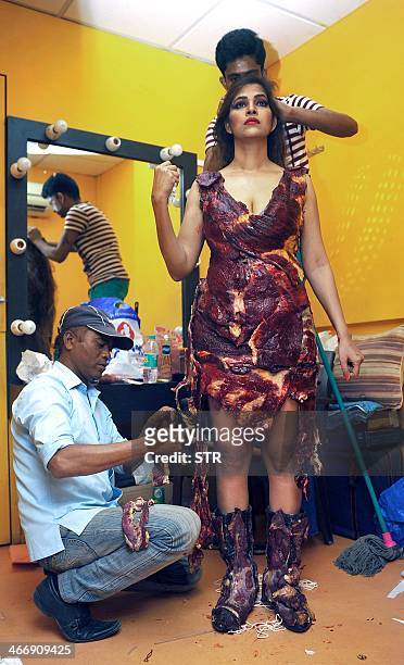 Indian Bollywood film actress Tanisha Singh is assisted as she prepares to pose in a real goat meat dress, similiar to one worn by Lady Gaga, during...