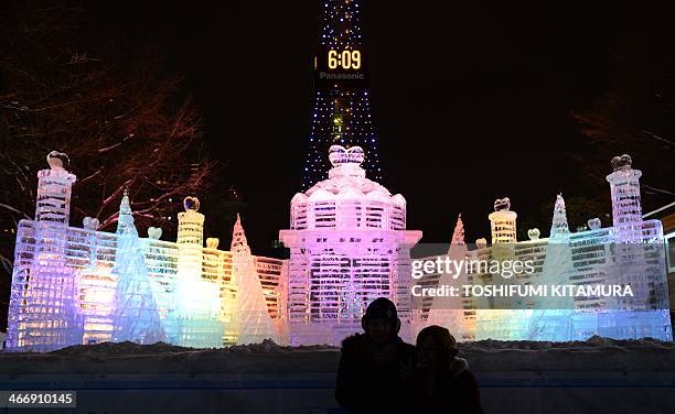 Visitors pose in front of an ice sculpture of the Palace of the Heart during the 65th annual Sapporo Snow Festival in Sapporo on February 5, 2014....