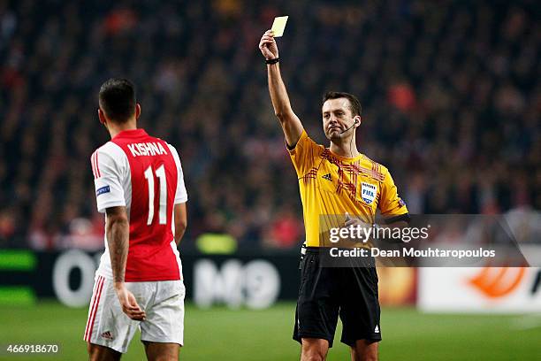 Ricardo Kishna of Ajax is shown the yellow card by referee Aleksei Kulbakov of Belarus during the UEFA Europa League Round of 16, second leg match...