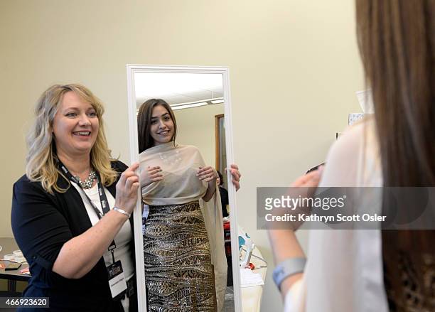 Jacqueline Mendoza-Barron, 18 looks at the gown she selected in the mirror held by Dawnalyn Edgar. TLC joins with The Cable Center in Denver to honor...