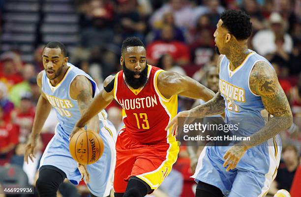 James Harden of the Houston Rockets dribbles between Darrell Arthur and Wilson Chandler of the Denver Nuggets during their game at the Toyota Center...