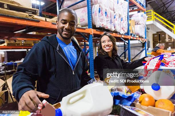 diverse volunteers cheerfully sorting food items - gallon stock pictures, royalty-free photos & images