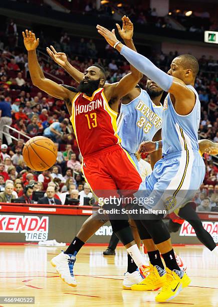 James Harden of the Houston Rockets drives between Kenneth Faried and Randy Foye of the Denver Nuggets during their game at the Toyota Center on...