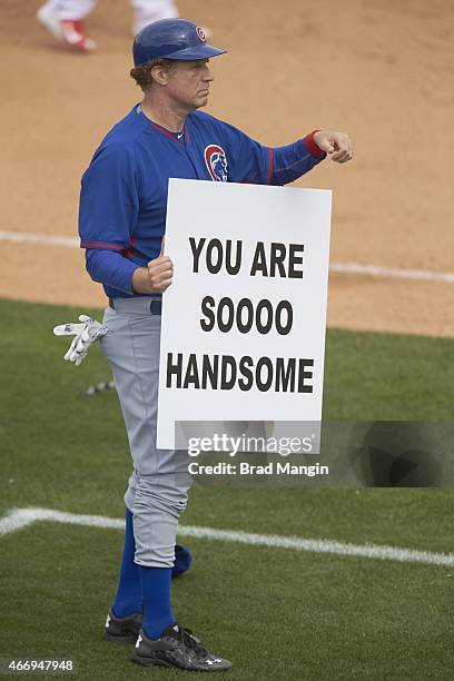 Chicago Cubs third base coach Will Ferrell holding up sign that reads YOU ARE SOOOO HANDSOME during spring training game vs Los Angeles Angels of...