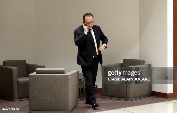 French President Francois Hollande uses his mobile phone before a European summit at the UE headquarter on March 20 in Brussels. AFP PHOTO/ ALAIN...