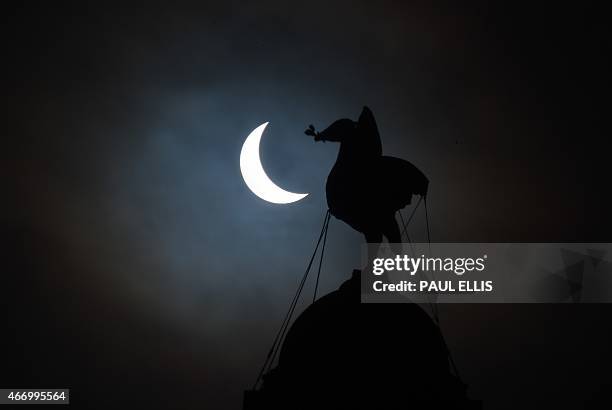 Partial solar eclipse of the sun is visible next to the iconic Liver Bird on top of the Liver Building in Liverpool, north-west England on March 20,...