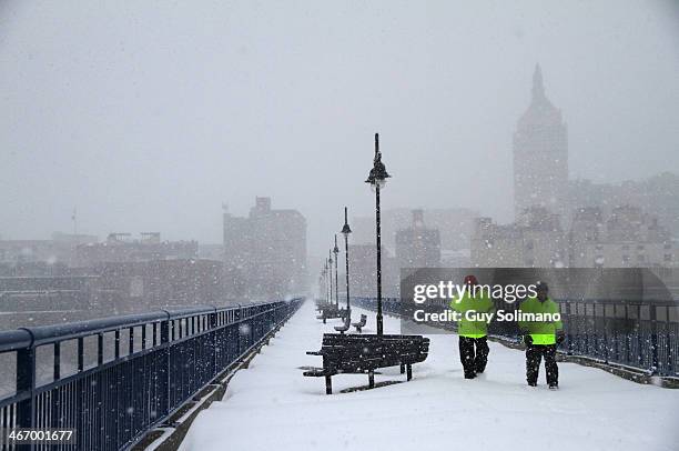 Fred Van Orden, left, and Andy Santell, members of Downtown Rochester Special Services, walk across the Pont de Rennes bridge during a snow storm on...