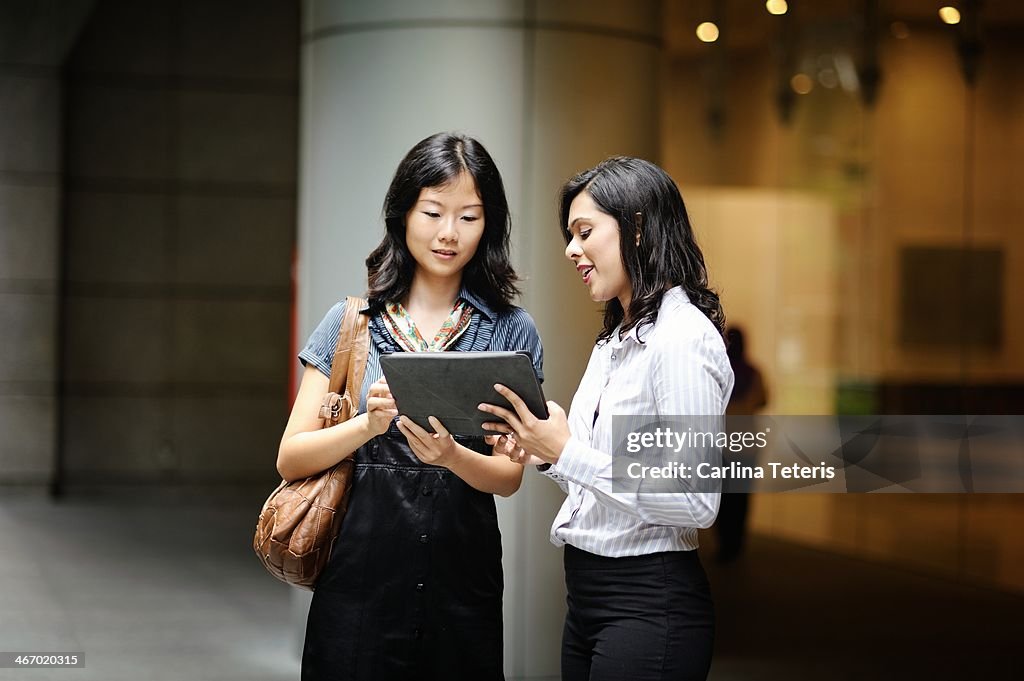 Two colleagues discussing work from a tablet