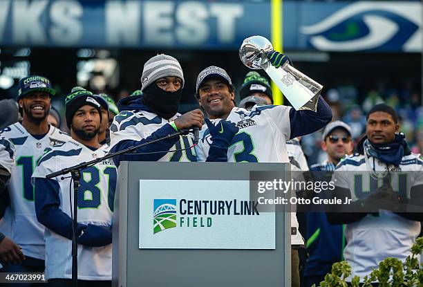 Quarterback Russell Wilson of the Seattle Seahawks holds the Lombardi Trophy as running back Marshawn Lynch looks on during ceremonies following the...