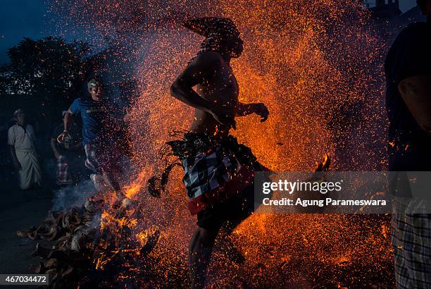 Balinese man kicks up the fire during the "Mesabatan Api" ritual ahead of Nyepi Day on March 20, 2015 in Gianyar, Bali, Indonesia. Mesabatan Api is...
