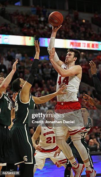 Frank Kaminsky of the Wisconsin Badgers shoots over Keenan Wetzel and Matt Costello of the Michigan State Spartans during the Championship game of...