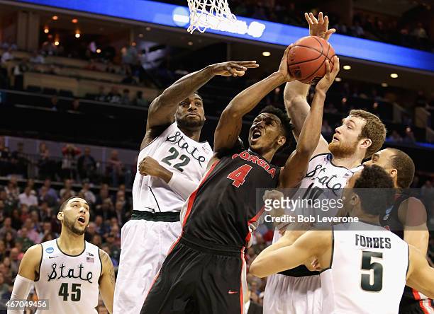 Teammates Branden Dawson and Matt Costello of the Michigan State Spartans try to stop Charles Mann of the Georgia Bulldogs during the second round of...