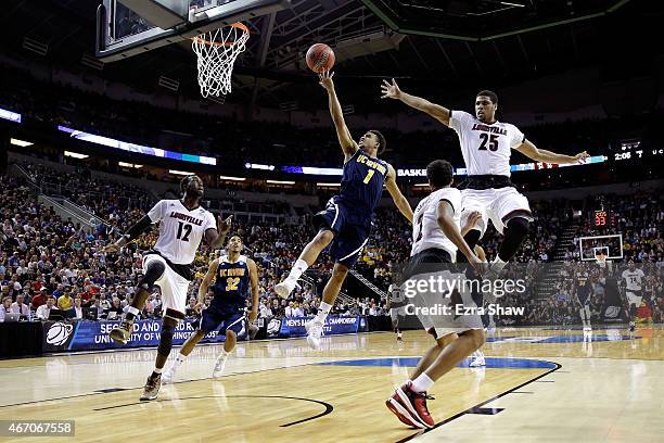 Alex Young of the UC Irvine Anteaters drives to the basket against Mangok Mathiang and Wayne Blackshear of the Louisville Cardinals in the second...