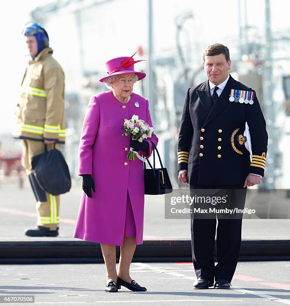 Queen Elizabeth II accompanied by Captain Timothy Henry uses an aircraft lift to reach the flight deck of HMS Ocean before departing by helicopter,...