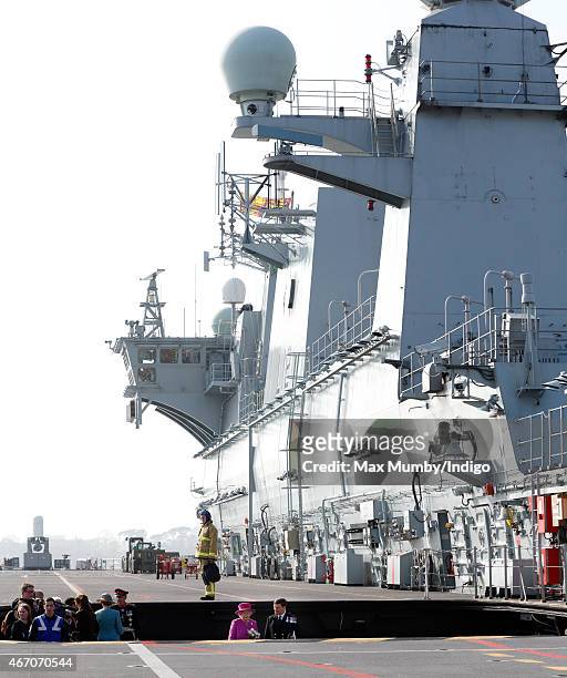 Queen Elizabeth II accompanied by Captain Timothy Henry uses an aircraft lift to reach the flight deck of HMS Ocean before departing by helicopter,...
