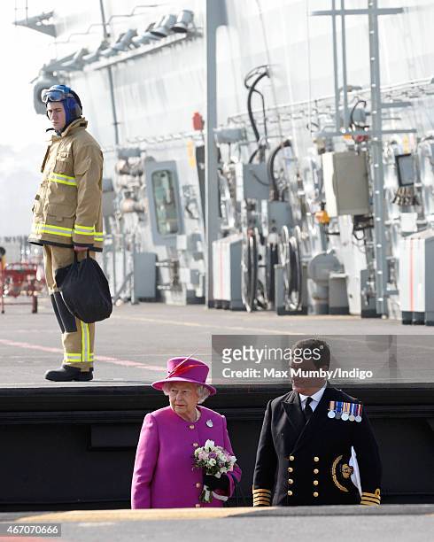 Queen Elizabeth II accompanied by Captain Timothy Henry uses an aircraft lift to reach the flight deck of HMS Ocean before departing by helicopter,...