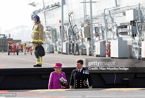 Queen Elizabeth II accompanied by Captain Timothy Henry uses an aircraft lift to reach the flight deck of HMS Ocean before departing by helicopter,...