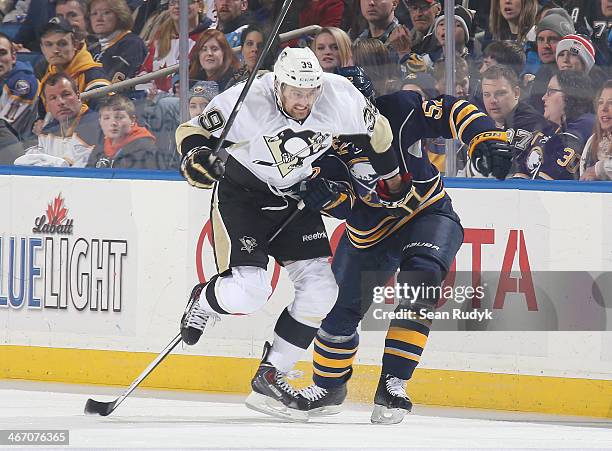 Harry Zolnierczyk of the Pittsburgh Penguins gets caught up in the stick of Alexander Sulzer of the Buffalo Sabres at First Niagara Center on...