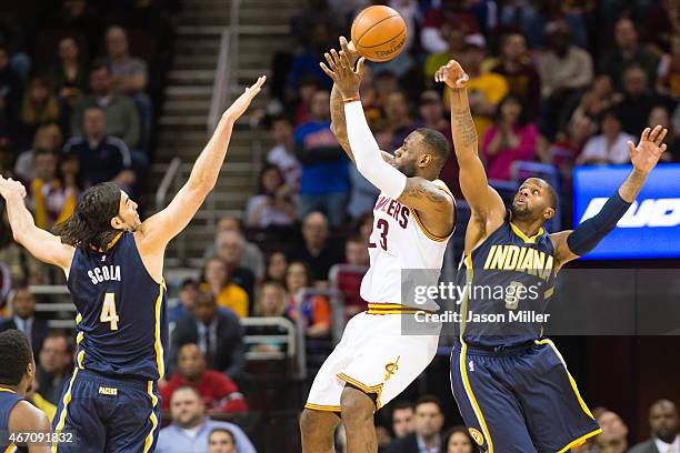 LeBron James of the Cleveland Cavaliers is blocked by C.J. Miles while under pressure from Luis Scola of the Indiana Pacers during the second half at...