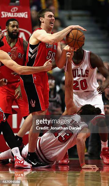 Joakim Noah of the Chicago Bulls tries to knock the ball away from Tyler Hansbrough of the Toronto Raptors after falling to the floor at the United...