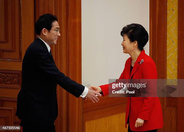 South Korea President Park Geun-hye shakes hands with Japanese Foreign Minister Fumio Kishida during their meeting at the Presidential Blue House on...