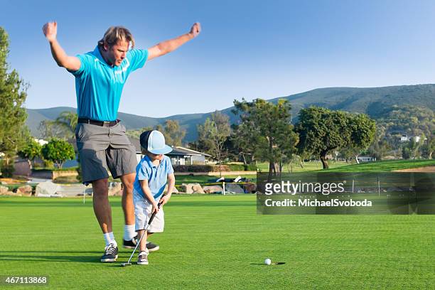 dad and little boy golfing celebration - putting clothes son stock pictures, royalty-free photos & images