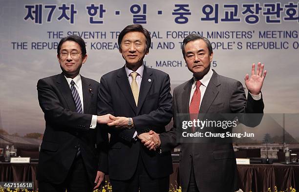 Japanese Foreign Minister Fumio Kishida, South Korean Foreign Minister Yun Byung-Se and Chinese Foreign Minister Wang Yi shakes hands before their...