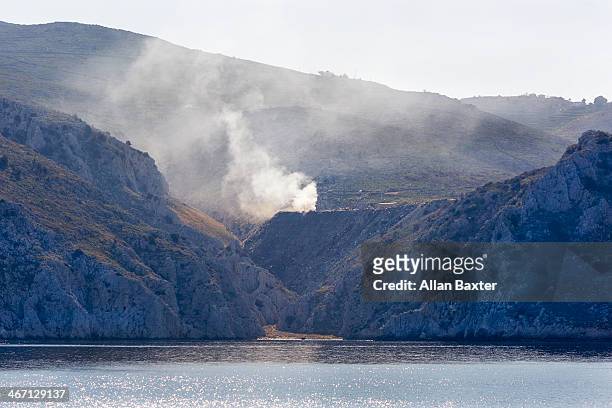 coastline of hydra with smoke - hydra greece fotos stockfoto's en -beelden