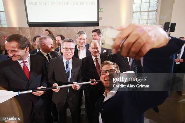President Alfons Hoermann, German Interior Minister Thomas de Maiziere and Hamburg mayor Olaf Scholz watch Moritz Fuerste shoot a selfie after...