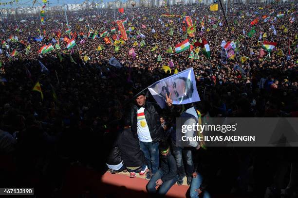 Man flashes the "V for Victory" sign and waves a flag with a picture of jailed Kurdish rebel leader Abdullah Ocalan as people gather to celebrate...