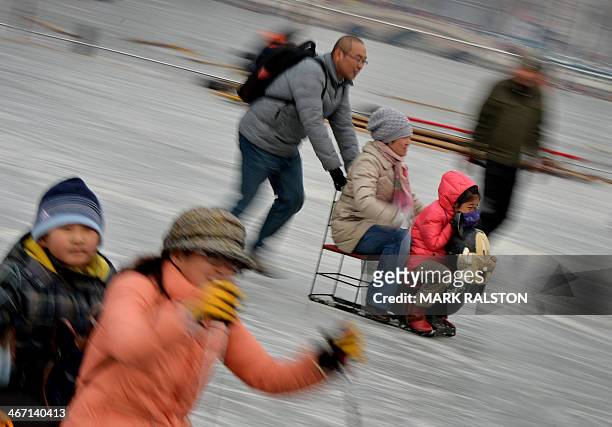 Chinese visitors enjoy sledding and skating on the partially frozen Houhai Lake during the Lunar New Year holiday in Beijing on February 6, 2014....