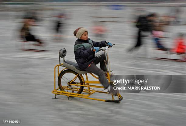 Chinese boy rides an ice bike on the partially frozen Houhai Lake during the Lunar New Year holiday in Beijing on February 6, 2014. Beijing saw its...