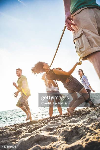 friends playing limbo on the beach during vacations - limbo stockfoto's en -beelden