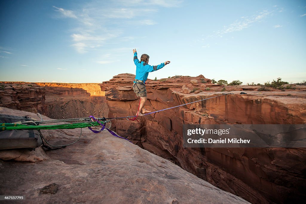 Guy walking on a line over a canyon in Moab.