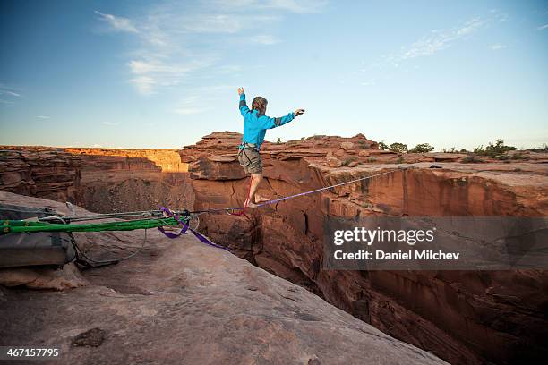 guy walking on a line over a canyon in moab. - coraggio foto e immagini stock