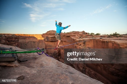 Guy walking on a line over a canyon in Moab. Guy walking on a line over a canyon in Moab.