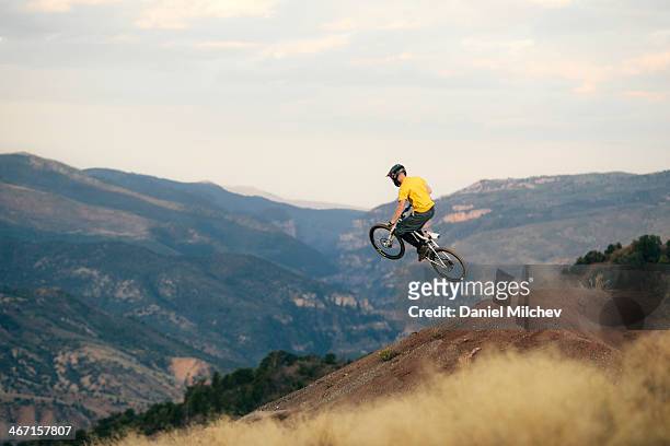 guy with a mountain bike, jumping off of a jump. - mountainbiking stock-fotos und bilder