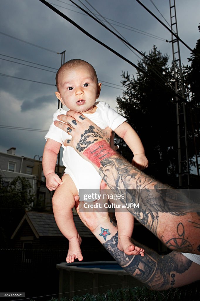 Father with tattooed arms holding baby son