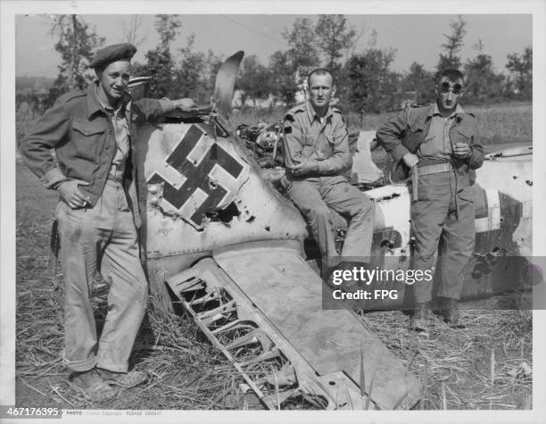 Canadian and US soldiers posing with a crashed Nazi plane near Aquino; Pte. M. D. Marquette, Tpr. W. J. MacDonald and Tpr. J. A. Siluck, Italy, circa...