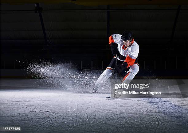 male ice hockey player taking puck - hockey photos et images de collection