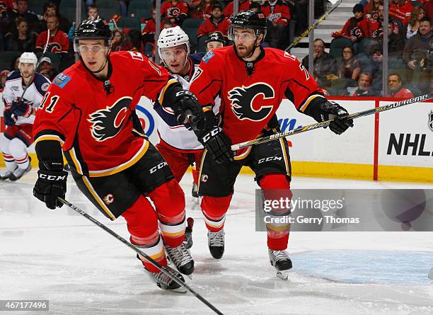 Mikael Backlund and TJ Brodie of the Calgary Flames hunt down the puck against the Columbus Blue Jackets at Scotiabank Saddledome on March 21, 2015...