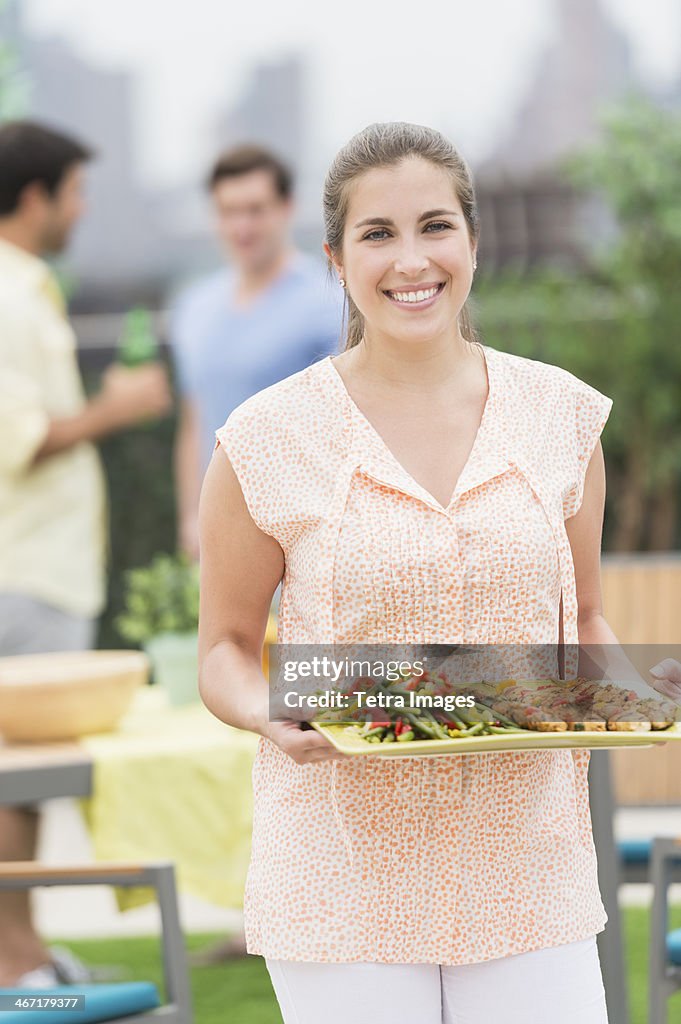 USA, New Jersey, Jersey City, Woman carrying tray with food in garden