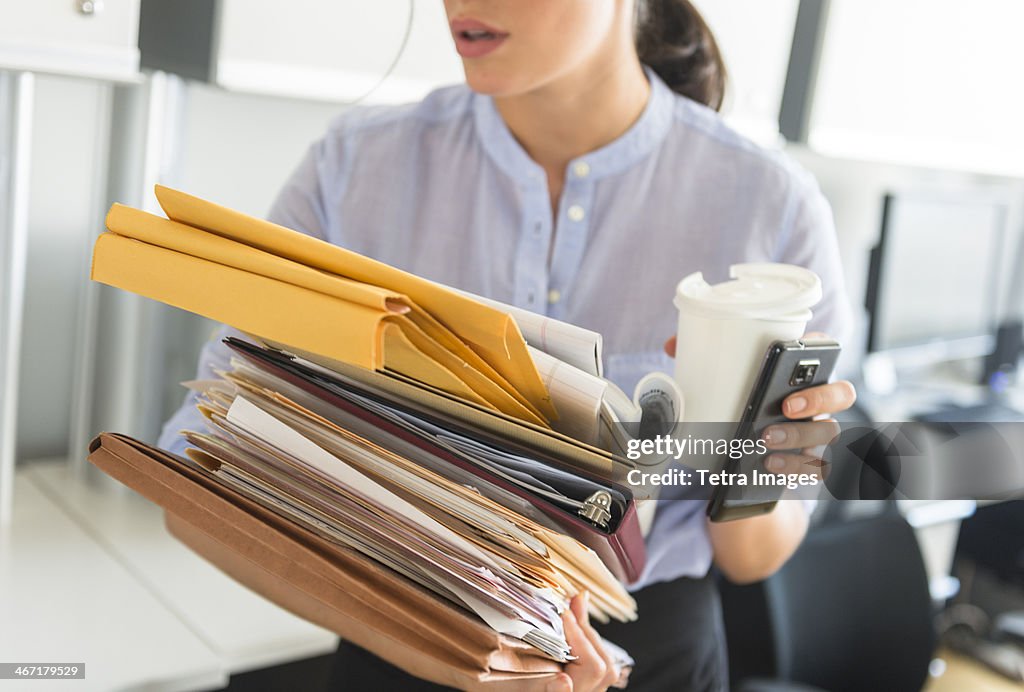 USA, New Jersey, Jersey City, Business woman holding stack of documents in office