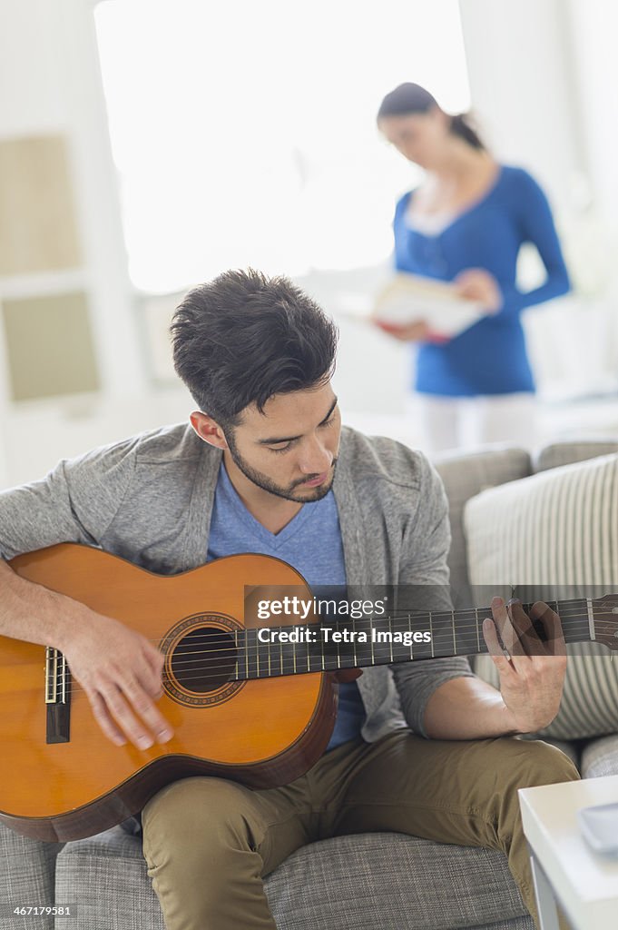 USA, New Jersey, Jersey City, Man playing guitar, woman in background