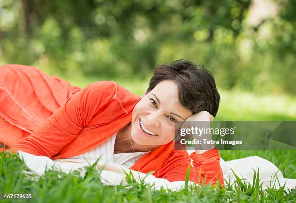 usa, new york state, new york city, mature woman lying on grass - mature adult focus on foreground stock-fotos und bilder