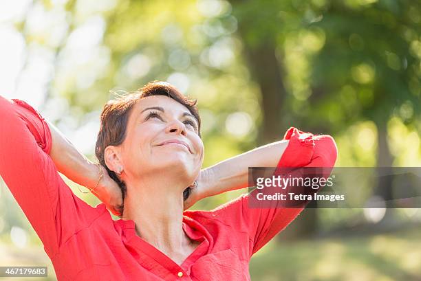 usa, new york state, new york city, happy mature woman raising hands in park - mature brunette woman stockfoto's en -beelden