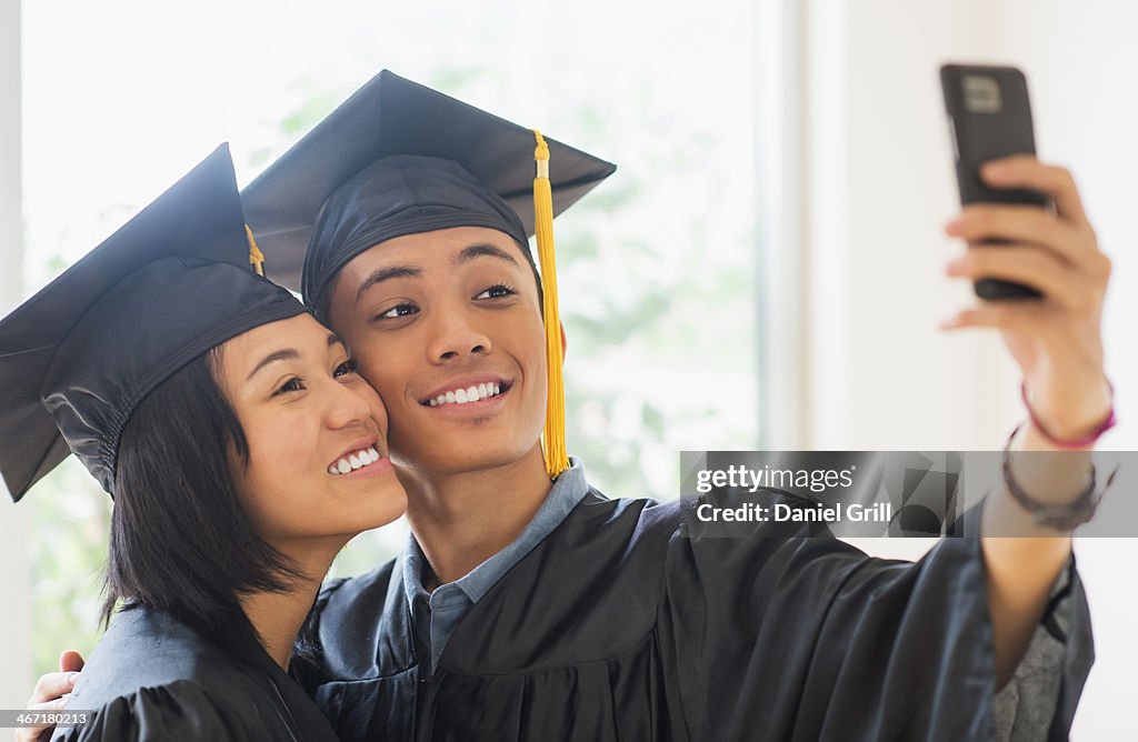 USA, New Jersey, Jersey City, Portrait of young woman and young man wearing graduation gown